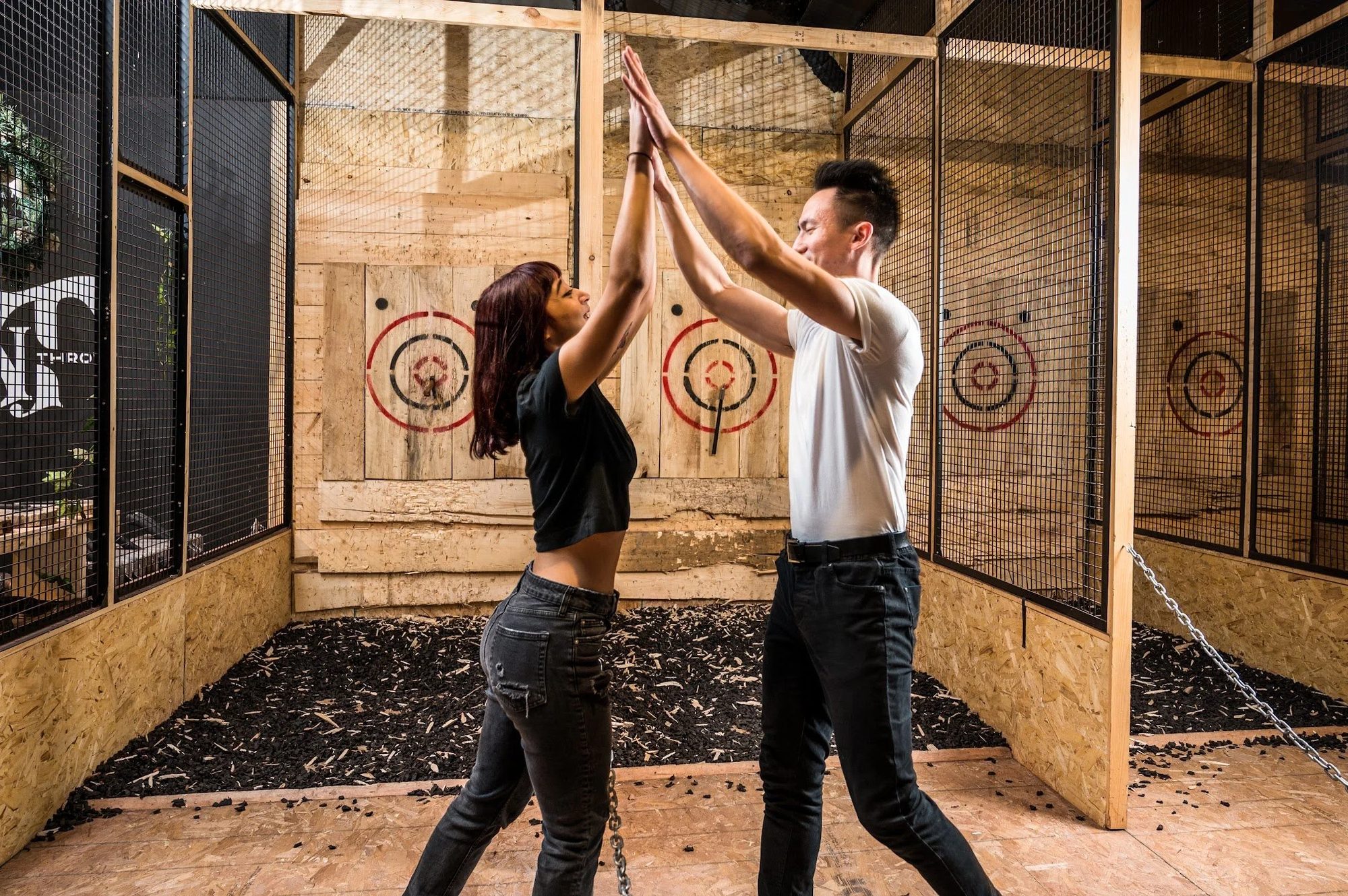 Two guests high-fiving in front of an axe throwing target